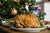 Turkey on a table in front of a Christmas tree.